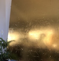 a large piece of gold foil sitting on a table next to a plant