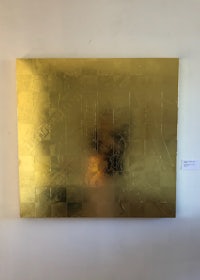 a gold piece of art hanging on a wall